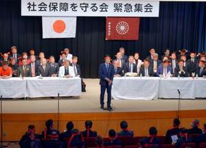 自民党本部で開かれた緊急集会であいさつする田村元厚労相(中央)=18日午後、東京・永田町