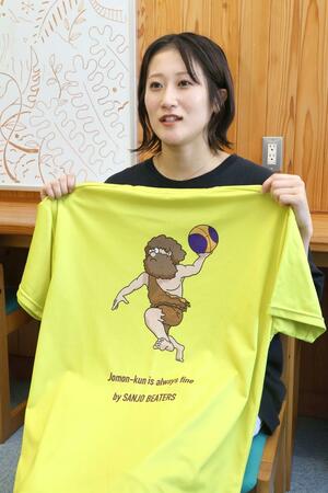 現在の練習用Ｔシャツを持つ三条ビーターズの竹内あかりさん。新たなシャツにはスポンサーの企業名やロゴが入る予定＝三条市荒沢