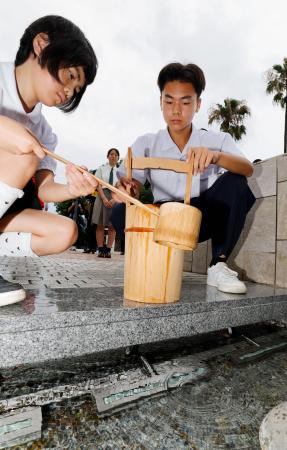 平和公園の「平和の泉」から献水用の水をくむ生徒ら=8日午前、長崎市