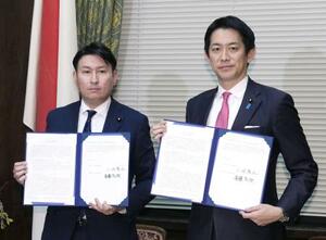 「OTC類似薬」の自己負担見直しについての合意文書を掲げる自民党の小林政調会長(右)と日本維新の会の斎藤政調会長=19日、国会