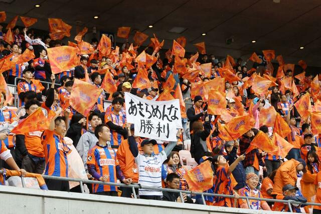 試合前、「あきらめんな勝利」と書いたフラッグを掲げるサポーター=ビッグスワン