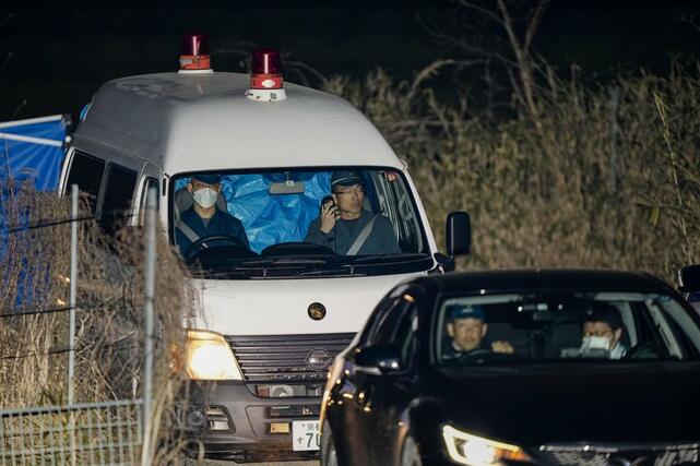 身元不明の遺体が見つかった京都府南丹市の現場付近を出る警察車両。後部座席がブルーシートで覆われていた＝１３日午後９時２３分