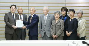 特定失踪者家族会の今井英輝会長(左から3人目)や大沢昭一さん(同4人目)らから要望書を受け取る林官房長官(左端)=5月20日、首相官邸