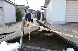液状化などの影響で地盤が変化し、表面のアスファルトはめくれ上がった=1月2日、新潟市西区寺尾東1