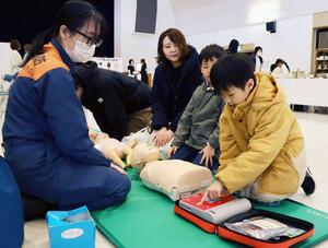 消防隊員からAEDの使い方を教わる親子連れ=20日、燕市吉田東栄町