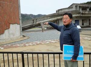 　震災遺構・旧大川小校舎で、外壁タイルが崩れた部分について説明する紫桃隆洋さん＝２０２５年３月、宮城県石巻市