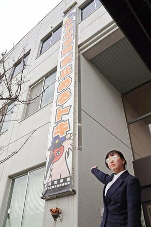 寄贈した懸垂幕を指し示す長谷川彩華さん＝長岡市水道町３