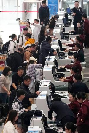 北京首都空港の日本便などを扱うカウンターで搭乗手続きをする人たち=15日(共同)