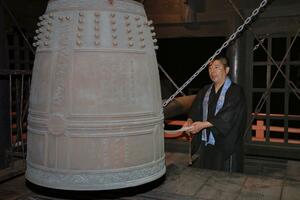 梵鐘を突く西楽寺の春日一浄さん=8月1日午後10時30分、長岡市千代栄町