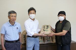 フードバンクあがの山田隆之代表(右)に米を贈る奥阿賀酒米研究会の会員ら=阿賀町津川