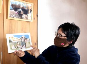 愛犬「福」の写真の前で、自費出版した絵本を紹介する菊地牧子さん=佐渡市沢根