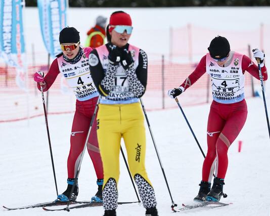 女子リレー 十日町の2走山田結衣(右)からアンカー牧田鈴葉(左)にリレー=2月11日、北海道名寄市