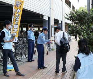 駅前の駐輪場で自転車の鍵掛けなどを呼びかける上越署員ら=上越市仲町