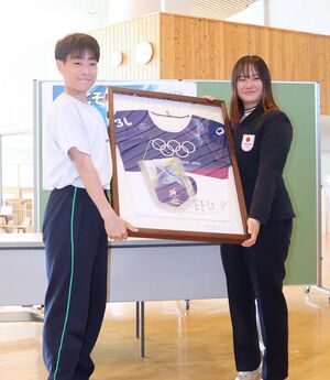 母校の湯沢中学校で講演し、五輪で着用したビブなどの寄贈品を生徒に手渡す吉田蓮生選手＝湯沢町神立