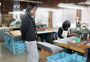 刃先を覆うビニール製パッケージなどを製造している「いづみ商会」の工場で語る代表の安達拓未さん（左）＝三条市西四日町３