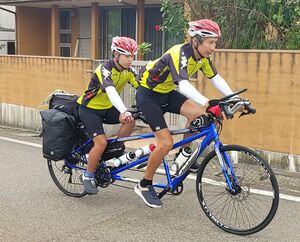自転車での日本縦断を目指し、力を合わせてペダルをこぐ阪野翔生さん(左)と父親の顕正さん=9月27日、上越市大潟区