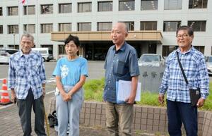 佐賀県警本部前で取材に応じる日本国民救援会佐賀県本部の山口勝弘事務局長(右から2人目)=24日午後
