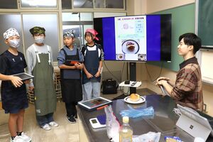 パン店「パトラッシュ」の築田祥吾店長に試食してもらう新井中央小の児童たち=妙高市諏訪町2