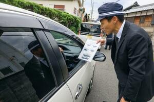 　検問で不審車と同型車の画像を示し、情報提供を求める大阪府警の捜査員＝２１日午後、大阪府熊取町