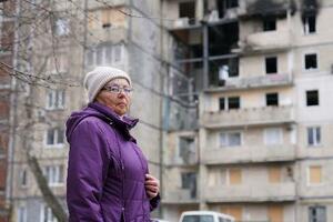 　ロシア軍の無人機が直撃した住宅の前に立つリュドミラ・ジライさん＝３月、キーウ（共同）