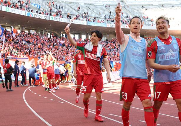 試合終了後、スタンドの声援に応える主将のDF藤原奏哉(中央)ら=デンカビッグスワン