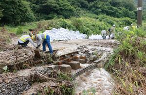 土砂が流入したＪＲ羽越線の現場で復旧を急ぐ作業員たち＝１５日午前１０時過ぎ、村上市吉浦