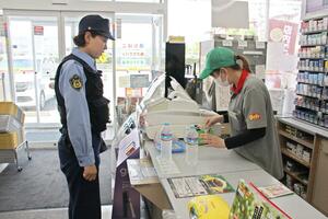 コンビニに立ち寄り、飲料水を購入する警察官=7月31日、新潟市中央区