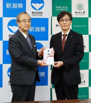 花角英世知事(左)から目録を受け取る新潟大の染矢俊幸学長=3月31日、県庁