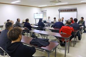 佐渡市のトキ保護の取り組みについて説明を受け、熱心に質問をぶつける羽咋市の視察団＝佐渡市新穂潟上