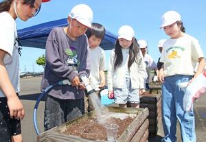 7・13水害の被害に思いを巡らし、ヒマワリの種をまく中之島中央小の児童=長岡市中之島