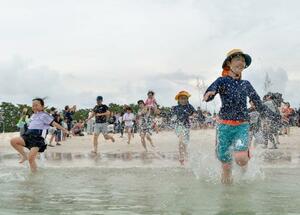 　和歌山県白浜町の白良浜が海開きし、海へ駆け込む海水浴客＝３日午前
