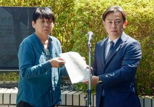 福岡厚労相(右)に要望書を手渡す全国薬害被害者団体連絡協議会の花井十伍代表世話人=26日午後、厚労省