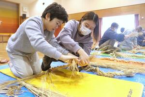 新年に向け、力を込めてしめ縄を作った参加者＝佐渡市新穂瓜生屋
