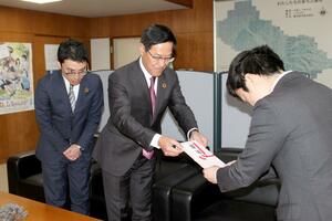 滝沢亮・三条市長にカーブミラー寄贈の目録を手渡す三条信用金庫の白倉徳幸理事長(中央)=三条市役所