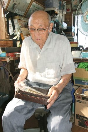 戦時中の写真を見る小保茂さん=佐渡市