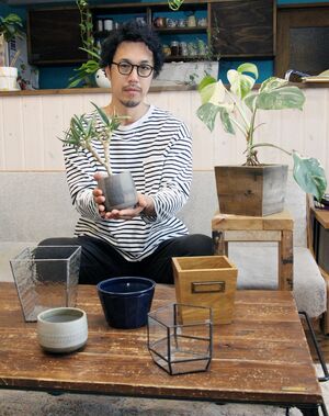 ネット販売で扱うガラスや木材などを使った植木鉢を紹介するFIOVANA代表の五傳木陽介さん=新潟市西蒲区
