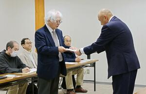 原発の運転中止を求め、東京電力側に申し入れ書を手渡す石崎誠也・新潟大名誉教授(手前左)=24日、刈羽村