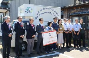 キッチンカーの前で寄付金の目録を持つNPO法人えんでばの関係者ら=新潟市江南区横越川根町
