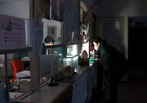 夕方、薄暗い診療所内でランタンの明かりを頼りに受け付けする患者ら=12月20日午後4時30分ごろ、佐渡市赤泊