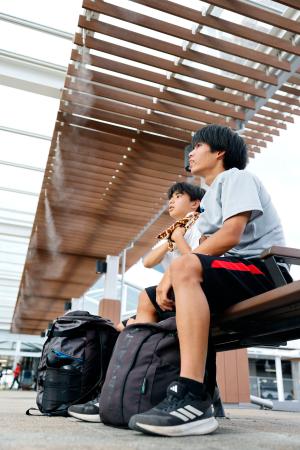 気温が国内最高を更新する41・8度に達した群馬県伊勢崎市でミストを浴びる人たち=5日午後