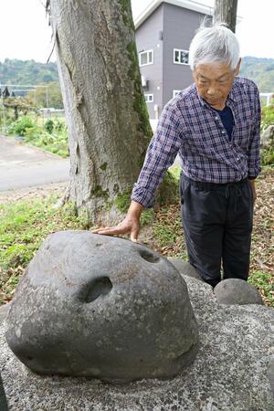 諏訪神社の境内にある「鮭頭石」。目黒恒夫さんは小さい頃から親しんだ=2024年10月、魚沼市四日町