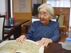 画文集を手に、自身の体験を語る仏画家豊田和子さん=7月、神戸市中央区