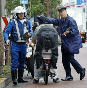 16歳以上の自転車の交通違反に反則金納付を通告できる交通反則切符(青切符)制度が始まり、東京都北区の交差点付近で利用者に指導する警察官=4月1日
