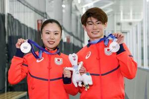 フィギュアスケート団体で獲得した銀メダルを掲げる、アイスダンスの吉田唄菜(左)と森田真沙也=京都府宇治市