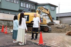 解体された実家の跡地で映画の撮影をする鈴木剛志さん(右)=2025年10月、新潟市西区