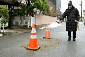 液状化現象で陥没し、砂利で応急補修をした道路。泥を詰めた袋も置かれていた=11日、新潟市江南区天野3