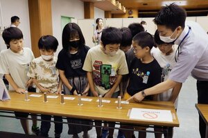 実際の硬貨や紙幣に触れる体験コーナーで、説明を聞く田上小の児童ら=加茂市本町