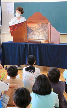 田口孝さんが新町小で披露した長岡空襲の紙芝居。田口さんの語りや絵の迫力に児童が引き込まれていた=長岡市西新町2