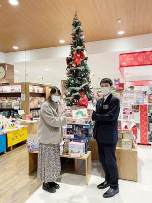 2023年のサンタプロジェクトしばたの様子。書店から本を受け取る敬和学園大の学生(左)=新発田市(敬和学園大提供)