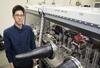 蓄電池の電解液の調合や評価を高速で行う自動実験ロボットの近くに立つ物質・材料研究機構の松田翔一さん=茨城県つくば市